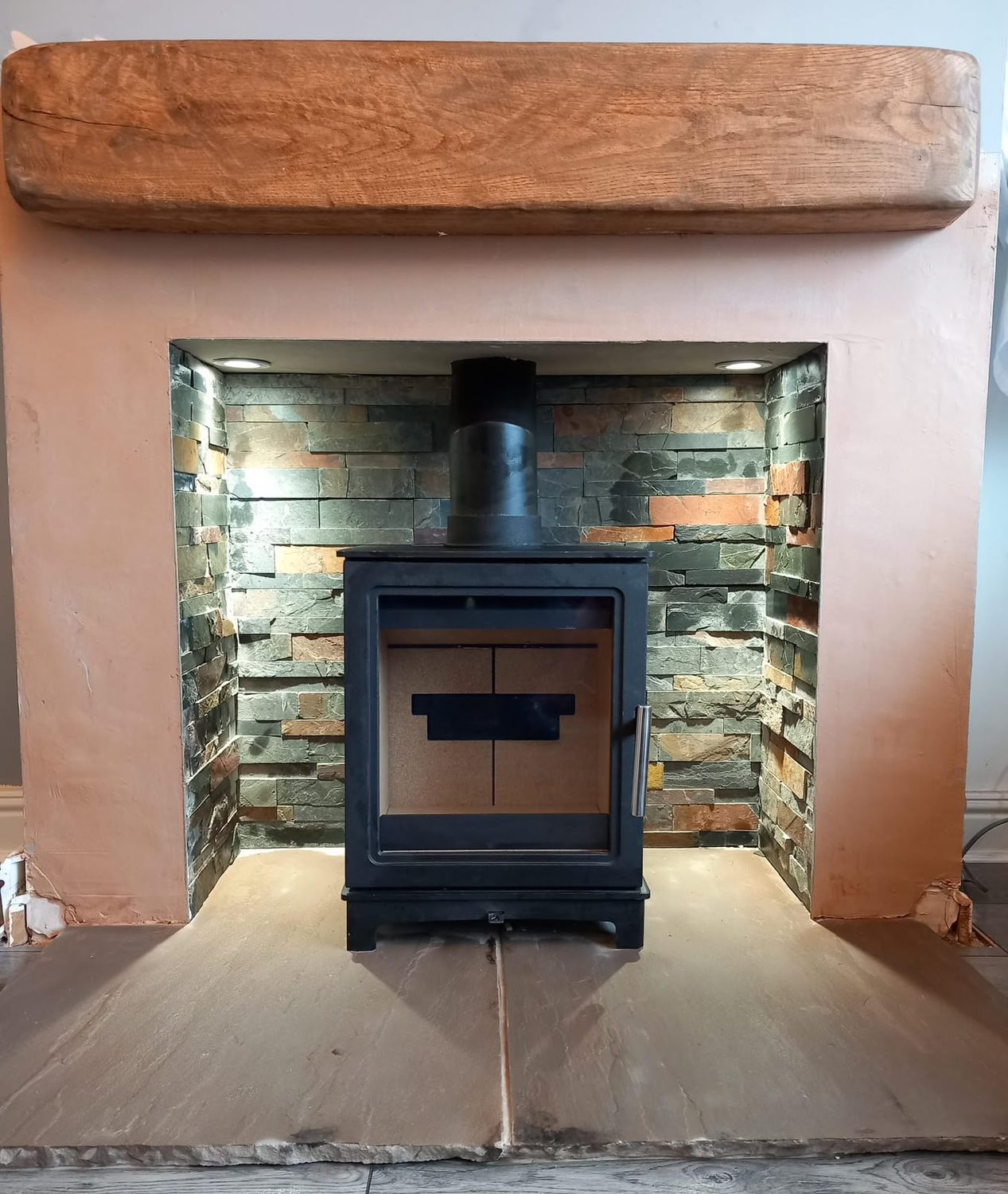 Stove in a multi-colour split-face slate chamber under an oak beam